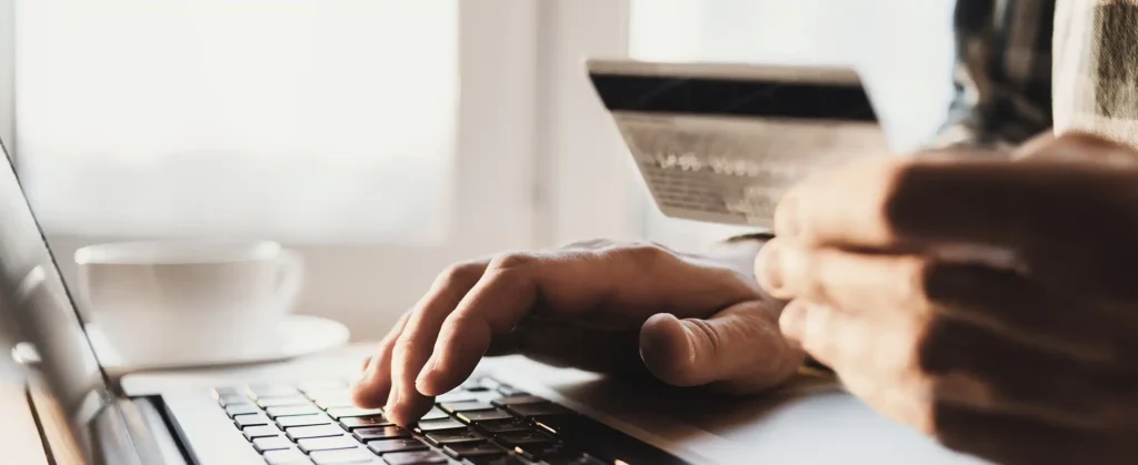 Man hand holding credit card and using laptop